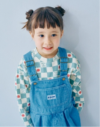 青いシャツにデニムのオーバーオールを着用した女の子モデルの画像