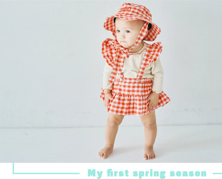 ギンガムチェックのロンパースを着用したベビーモデルの画像